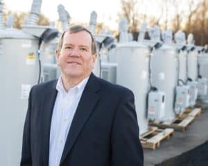 Craig Spencer smiles for the camera, with power transformers in background