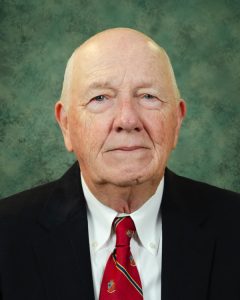 Mr. Settlemyre in a jacket and tie with an abstract green background