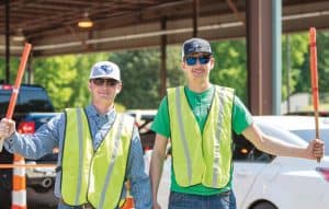 Good and Grier outside at the Annual Meeting drive-thru wearing safety vests and directing traffic